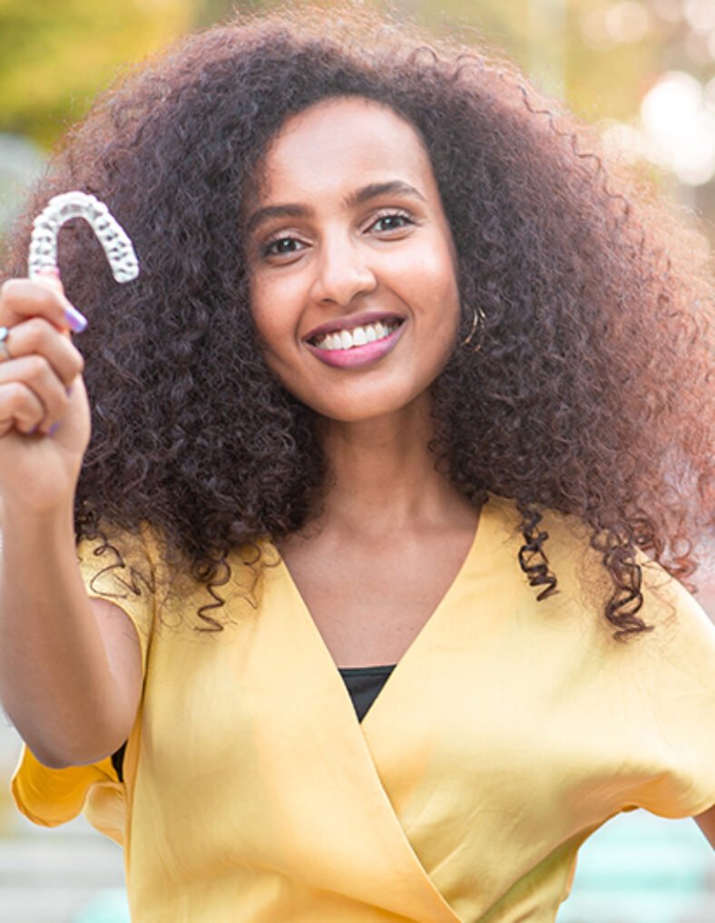 TEETH STRAIGHTENING lady holding clear aligner